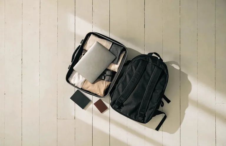 A neatly packed carry-on and backpack representing a minimalist nomad's belongings